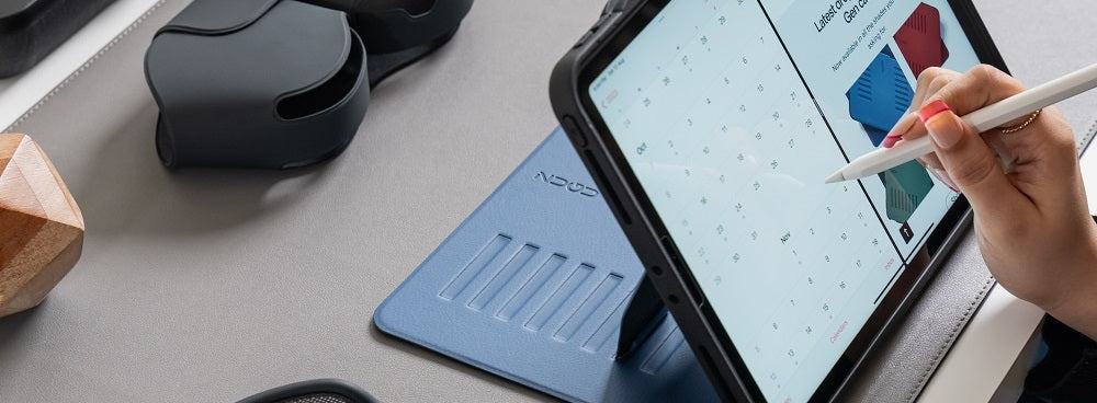 Tablet in a blue case on a desk with a stylus, open to a calendar and shopping app