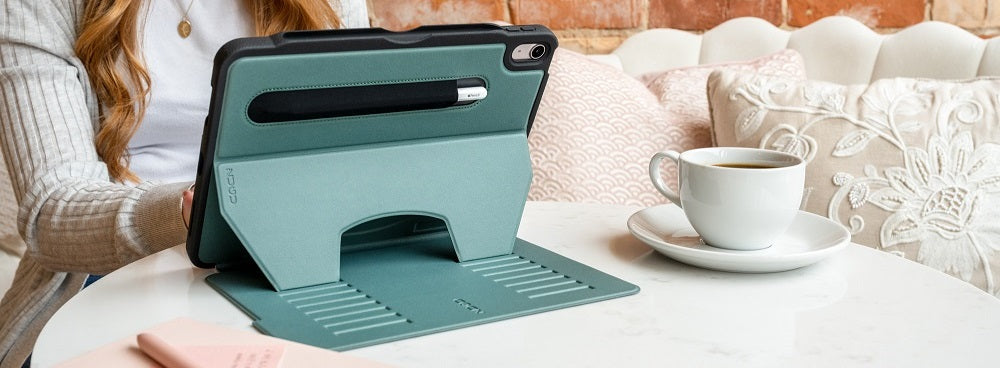 Woman sitting at a table with a tablet in a protective case